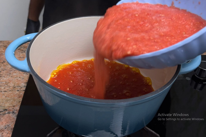 pouring tomatoes for cooking miyan taushe